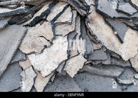 Gros plan de morceaux d'asphalte et de béton cassés sur la surface de la route. Banque D'Images