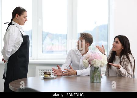 Couple se plaignant au serveur à propos du gâteau à table dans le restaurant Banque D'Images