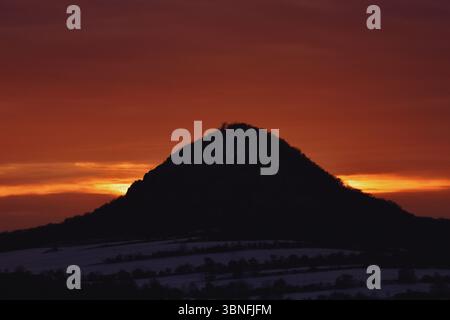 Coucher de soleil coloré et vif illuminant le ciel derrière une colline tchèque volcanique silhouette Banque D'Images