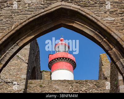 Phare rouge et blanc vu à travers l'arc de pierre des ruines de l'ancienne abbaye Saint-Mathieu, en Bretagne, France, par un après-midi ensoleillé. Banque D'Images
