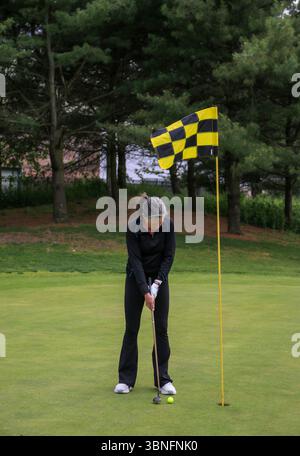 Golfeur se concentre sur la fabrication d'un putt près du trou sur un après-midi ensoleillé à l'extérieur. Banque D'Images