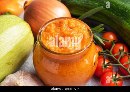 Caviar fait maison à partir de tomates courgettes et d'oignons dans un bocal en verre sur un fond gris. Conserves de production maison, conserves de légumes cuits en conserves Banque D'Images