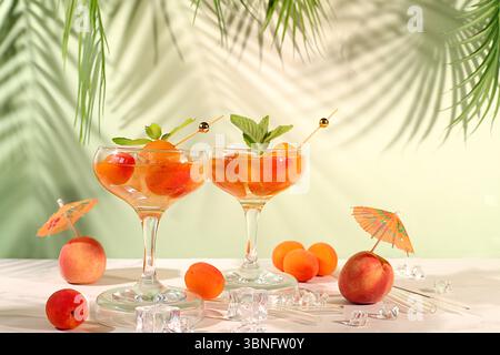 Nature morte moderne avec cocktail alcoolisé ou punch, baies de pêche, d'abricot et de menthe sur fond élégant, concept minimaliste pour bar et partie vacances Banque D'Images