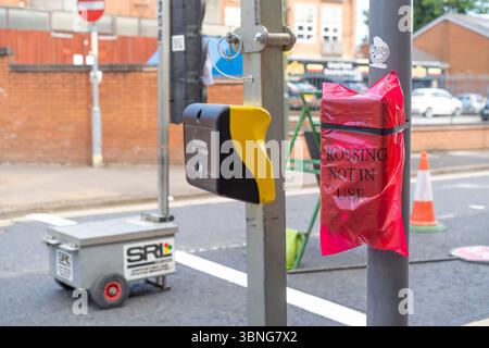 Passage non utilisé, housse de sac, au-dessus d'une boîte à boutons-poussoirs de passage piéton avec feux de circulation temporaires en place. Banque D'Images