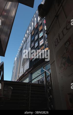 En regardant l'emblématique bâtiment Yodobashi Camera à Akihabara, Tokyo, encadré par des ruelles urbaines étroites et un ciel bleu vif Banque D'Images