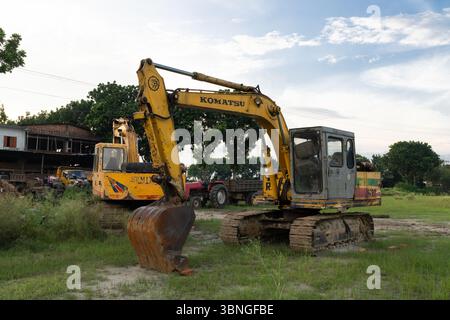 Une excavatrice jaune et rouillée sur un terrain vert Banque D'Images