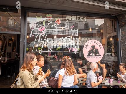 WIMBLEDON, LONDRES- 2 juillet 2025 : décorations de tennis et personnes dans la rue principale de Wimbledon Village pendant les championnats de Wimbledon 2025. Banque D'Images