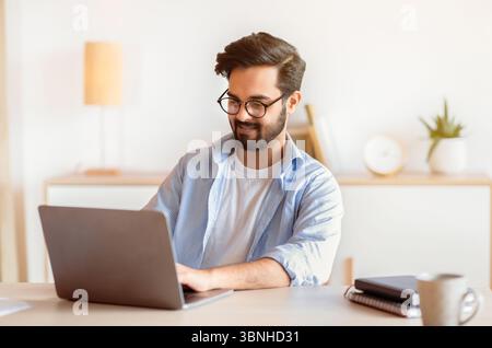 Homme arabe souriant Entrepreneur indépendant travaillant avec un ordinateur portable au bureau à domicile Banque D'Images