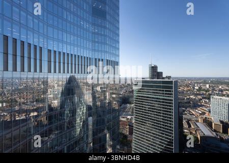 Une vue de 100 Bishopsgate, Londres, reflétant le Gherkin. Les gratte-ciel dominent la ligne d'horizon, mettant en valeur l'architecture moderne. Banque D'Images