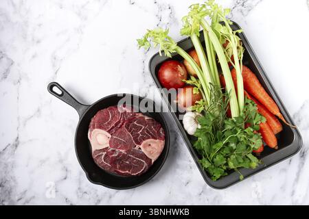 Sknuckle sur l'os, viande crue pour ossobuco, dans une poêle en fonte, plaque de cuisson avec des légumes, vue de dessus, pas de gens Banque D'Images