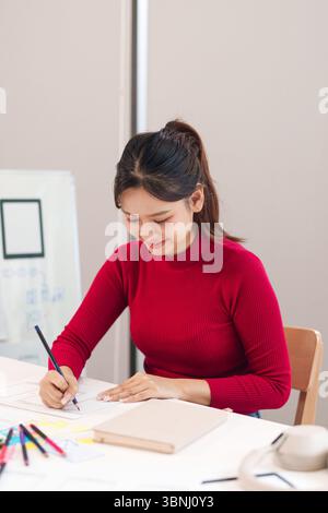 Femme asiatique adulte conçoit des interfaces utilisateur. Elle dessine des wireframes pour une application mobile et un site Web. Se concentrer sur la planification et la conception pour le numérique Banque D'Images