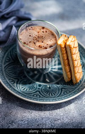 Une délicieuse pâte feuilletée garnie d'une riche confiture d'abricots accompagnée d'une tasse de cacao fraîchement infusé, présentée sur une plaque bleue magnifiquement conçue Banque D'Images