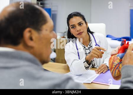 Une jeune femme médecin dispense des soins professionnels à un patient masculin âgé dans un hôpital latino-américain, favorisant un soutien et une compassion Banque D'Images