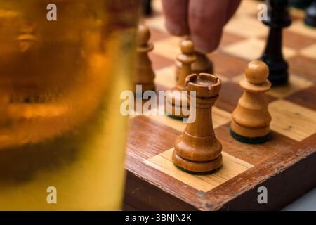 Jeu d'échecs en cours avec verre à bière au premier plan Banque D'Images