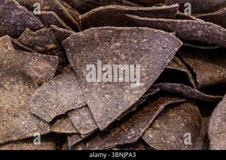Une image en gros plan montrant la texture détaillée des chips de tortilla de maïs bleues, soulignant leur aspect naturel et rustique. Idéal pour une alimentation saine BA Banque D'Images