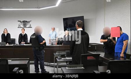 Stuttgart, Allemagne. 03 juillet 2025. Un accusé se tient dans la salle d'audience avec des menottes et un dossier devant son visage avant le début de son procès. conduit dans la salle d'audience. Un demandeur d'asile iranien aurait assassiné une enseignante de 66 ans à Nürtingen à la mi-octobre 2024 et jeté son corps dans le fleuve Neckar. Crédit : Bernd Weißbrod/dpa - ATTENTION : officiel a été pixélisé pour des raisons légales/dpa/Alamy Live News Banque D'Images