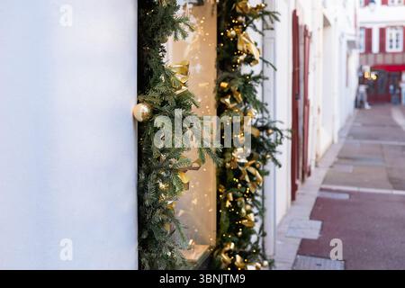 Une charmante rue ornée de verdure festive de Noël et de rubans dorés, créant une atmosphère de vacances chaleureuse et accueillante. Parfait pour célébrer Banque D'Images