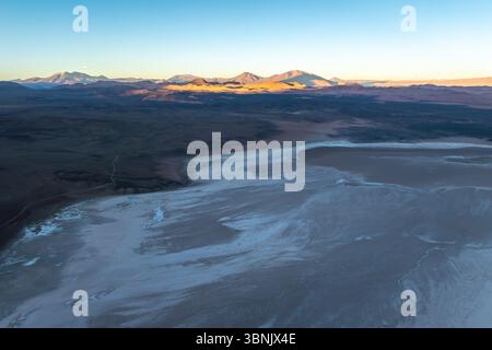 Une vue aérienne panoramique capture les paysages salins époustouflants de la Puna, en Argentine. La lumière du soleil illumine les vastes étendues salines sur fond de Banque D'Images