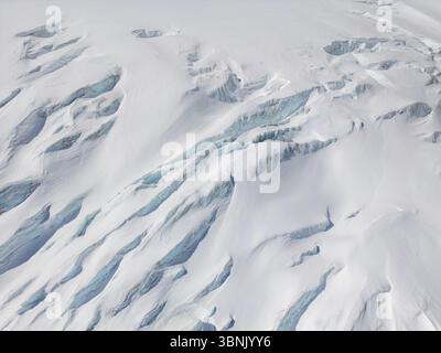 Une vue aérienne à couper le souffle d'un glacier dans les Alpes suisses, mettant en valeur de vastes champs de glace et de neige avec des crevasses profondes, soulignant la beauté et fra Banque D'Images