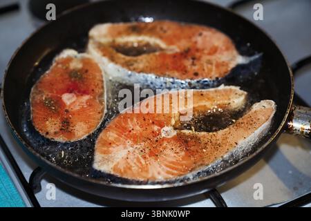 Gros plan de steaks de saumon frais grésillant dans une poêle, assaisonnés d'herbes et d'épices. Représentation parfaite de cookin sain et délicieux Banque D'Images