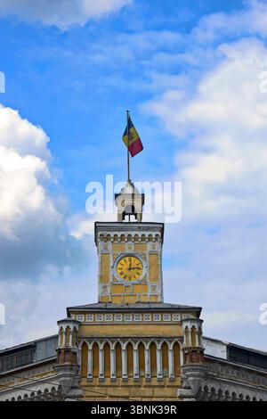 Drapeau moldave est fixé sur la tour de l'horloge de l'ancien bâtiment de la municipalité sur fond de ciel nuageux. Chisinau, Moldavie Banque D'Images