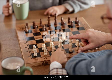Homme senior enseignant aux petits-enfants jouant aux échecs Banque D'Images