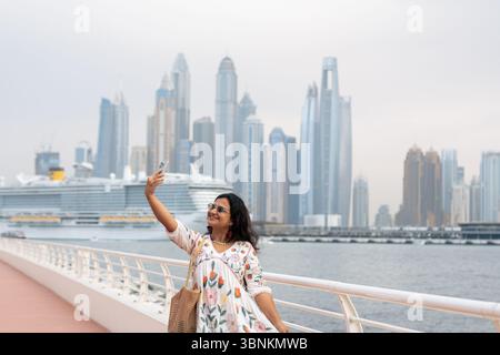 Fond de Dubai Marina avec croisière naviguant dans la mer et une jeune femme touristique cliquant sur des photos, voyage de luxe à Dubaï et photos de stock de style de vie Banque D'Images