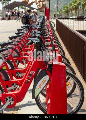 Une station d'accueil pour 'Bicing', le service public de partage de vélos de Barcelone. Vélos rouges alignés pour la location, promouvant le transport urbain durable. Banque D'Images