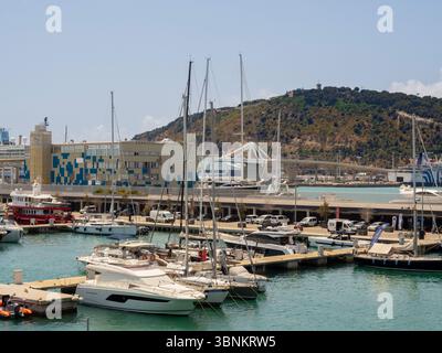 Vue depuis le port de Barcelone à travers la marina en direction de la colline de Montjuïc. Les yachts de luxe sont amarrés au premier plan par une journée ensoleillée. Barcelone. Espagne. Banque D'Images