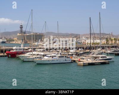 Yachts et bateaux amarrés à la marina de Port Vell avec l'horizon de Barcelone et Montjuïc en arrière-plan, Barcelone, Espagne. Banque D'Images