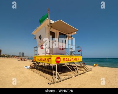 Une tour de sauveteur sur une plage de Barcelone, avec 'Salvament' (catalan pour Rescue) écrit sur le côté et un drapeau vert indiquant les conditions de baignade sûres Banque D'Images