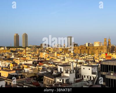 Vue surélevée sur les toits historiques de Barcelone au coucher du soleil, avec la basilique gothique de Santa Maria del Mar et les gratte-ciel modernes. Banque D'Images