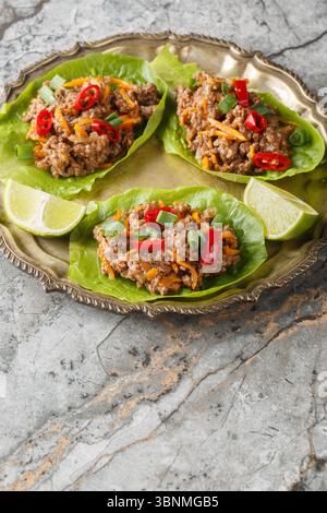 Coupes de laitue au bœuf thaïlandais juteuses gros plan sur l'assiette sur la table. Vertical Banque D'Images