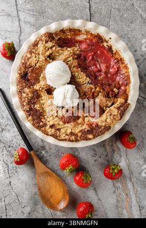 Cordonnier de fraise au chocolat avec crème glacée à la vanille gros plan dans un plat de cuisson sur la table. Vue de dessus verticale Banque D'Images