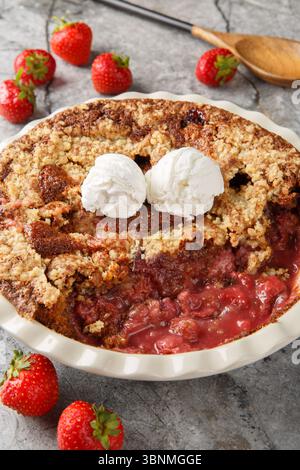 Cordonnier de fraise au chocolat avec crème glacée à la vanille gros plan dans un plat de cuisson sur la table. Vertical Banque D'Images