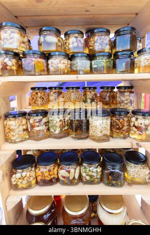 Des pots de miel avec diverses garnitures de noix se tiennent sur l'étagère. Produits à base de miel. Banque D'Images