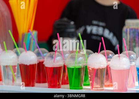 Boissons gazeuses colorées dans des gobelets en plastique avec un gros plan de paille. Banque D'Images