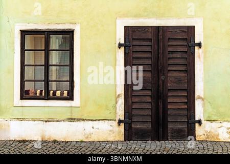 Porte et fenêtre en bois rustique sur le mur jaune vieilli Banque D'Images