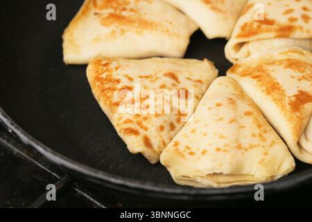 Crêpes pliées sur plaque noire. Crêpes minces dorées en forme triangulaire. Petit déjeuner traditionnel. Savoureux repas sucré ou salé. Plat maison. Banque D'Images