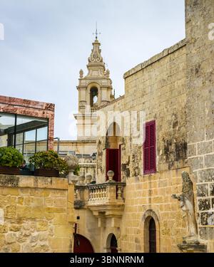 Vue panoramique sur le clocher de la cathédrale Saint Paul à Mdina, toits de la ville silencieuse, avec statue au premier plan un jour de pluie hivernale Banque D'Images