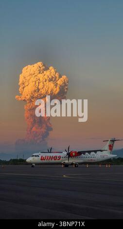 FLORES, INDONÉSIE 17 juin 2025 : un Wings Air ATR 72 est stationné alors que les cendres volcaniques de l’éruption du mont Lewotobi s’élèvent en arrière-plan pendant le coucher du soleil Banque D'Images