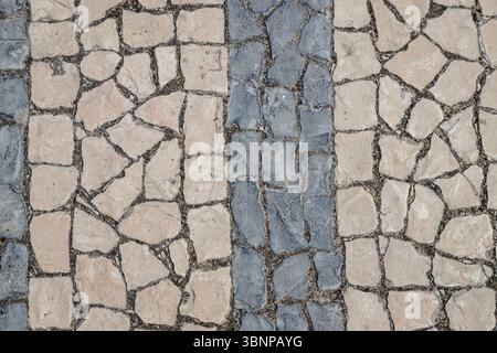 Pavé traditionnel portugais en pierre, connu sous le nom de 'calçada portuguesa', avec un motif rayé en calcaire noir et blanc, à Lisbonne, Portugal. Banque D'Images