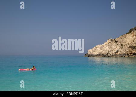 Femme se relaxant sur Pink Float dans la mer Turquoise Banque D'Images