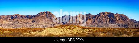 Vue panoramique sur les montagnes désertiques accidentées dans le parc national de Big Bend sous un ciel bleu vif. La géologie crée un contraste spectaculaire à travers le paysage. Banque D'Images