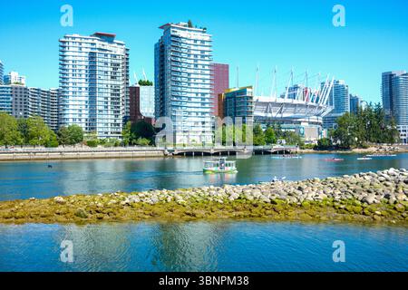 Un Aquabus et un groupe de bateaux-dragons se déplacent le long de False Creek devant le BC place Stadium et Habitat Island à Vancouver, en Colombie-Britannique. Banque D'Images