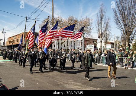 Lindenhurst, New York, États-Unis, 30 mars 2024 - des marcheurs en uniforme portant des drapeaux américains marchent fièrement dans Une rue ensoleillée pendant Une parade, avec Un Livel Banque D'Images