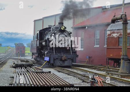 Vue sur une locomotive à vapeur ancienne réchauffant de la vapeur et de la fumée en début de matinée printanière Banque D'Images