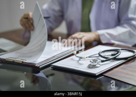 Médecin travaillant sur le bureau de la clinique, Focus sélectif sur le stéthoscope Banque D'Images