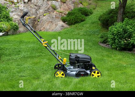 Nouvelle tondeuse à gazon dans le jardin de l'herbe verte longue, prête pour le travail de coupe Banque D'Images