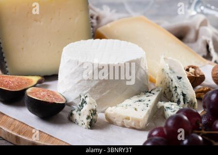 Plateau de charcuterie avec fromage, raisins et figues sur table en bois Banque D'Images